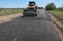 Geotextile road fabric on a rural access road with a skid steer spreading gravel
