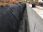 Non-woven geotextile filter fabric behind a retaining wall with gravel and drainage pipe
