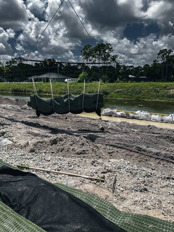 Crane placing Pyramat high performance turf reinforcement mat on a canal channel bank
