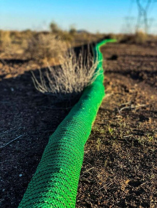 Close-up of a silt sock installed for erosion control in desert soil at sunrise
