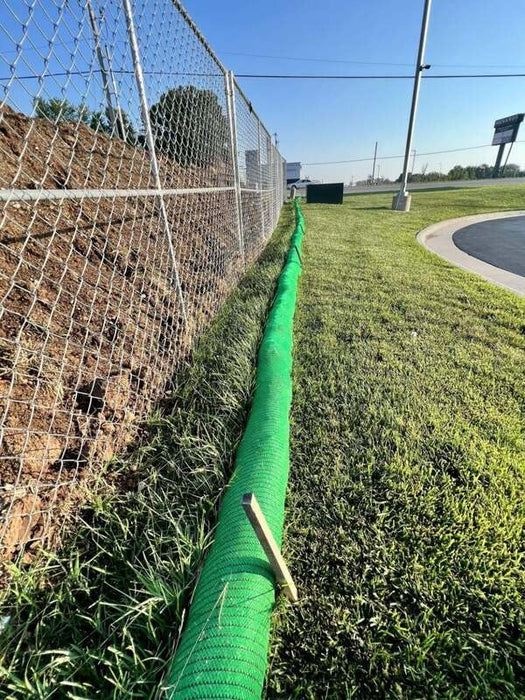 Green silt sock installed for perimeter control along a chain link fence at a new construction site
