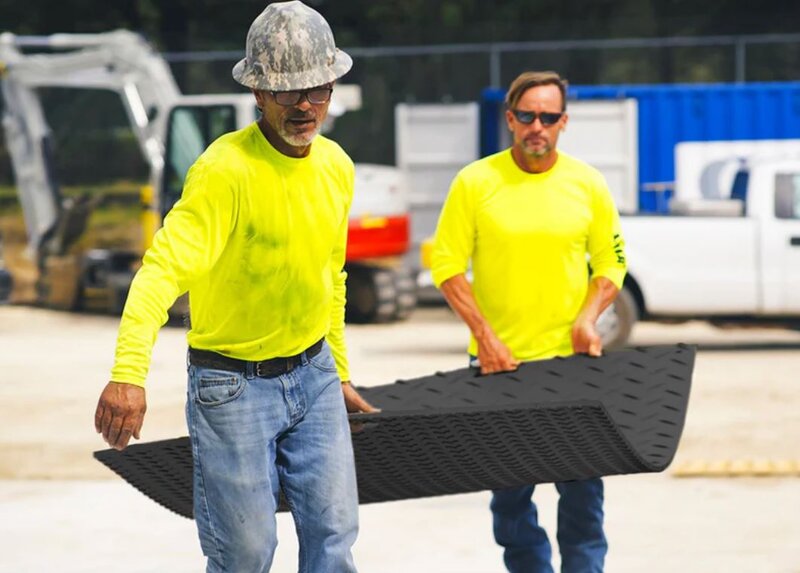 Two workers carrying a lightweight Blue Gator ground protection mat

