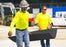 Two workers carrying a lightweight Blue Gator ground protection mat
